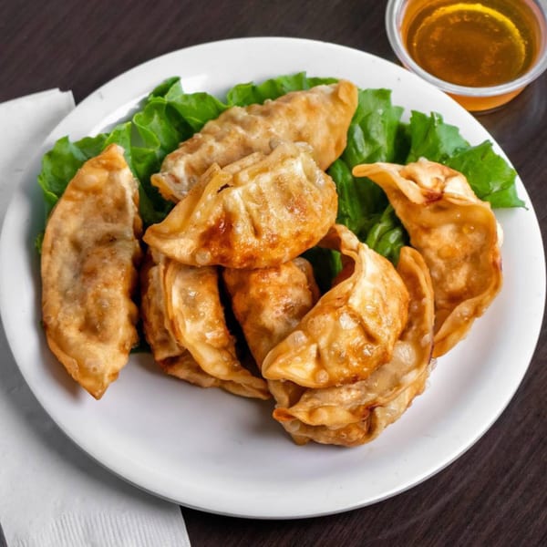 Golden-brown fried dumplings, served on a bed of fresh green lettuce with a side of dipping sauce.
